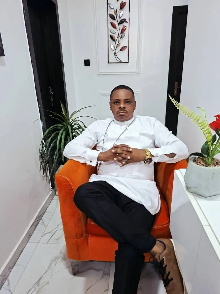 Bishop Francis Ugochukwu seated, in a white tunic