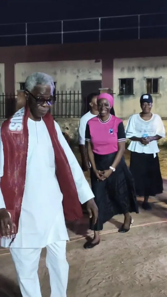 An elder in white robes with a red stole walking ahead of the Convener at the crusade ground
