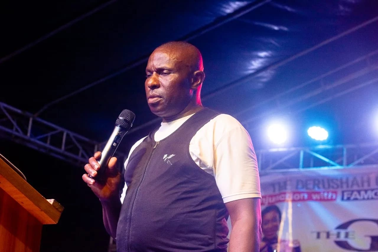 A minister speaking into a microphone at the lectern under the stage lights