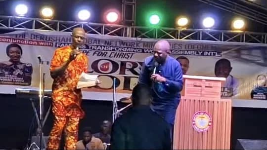 Two ministers on the lit stage beneath the Epe for Christ banner, one preaching with a microphone