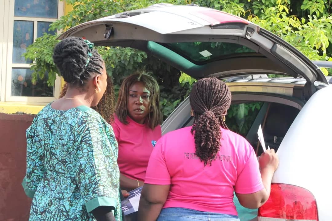 Members in pink shirts collecting leaflets from the boot of a car