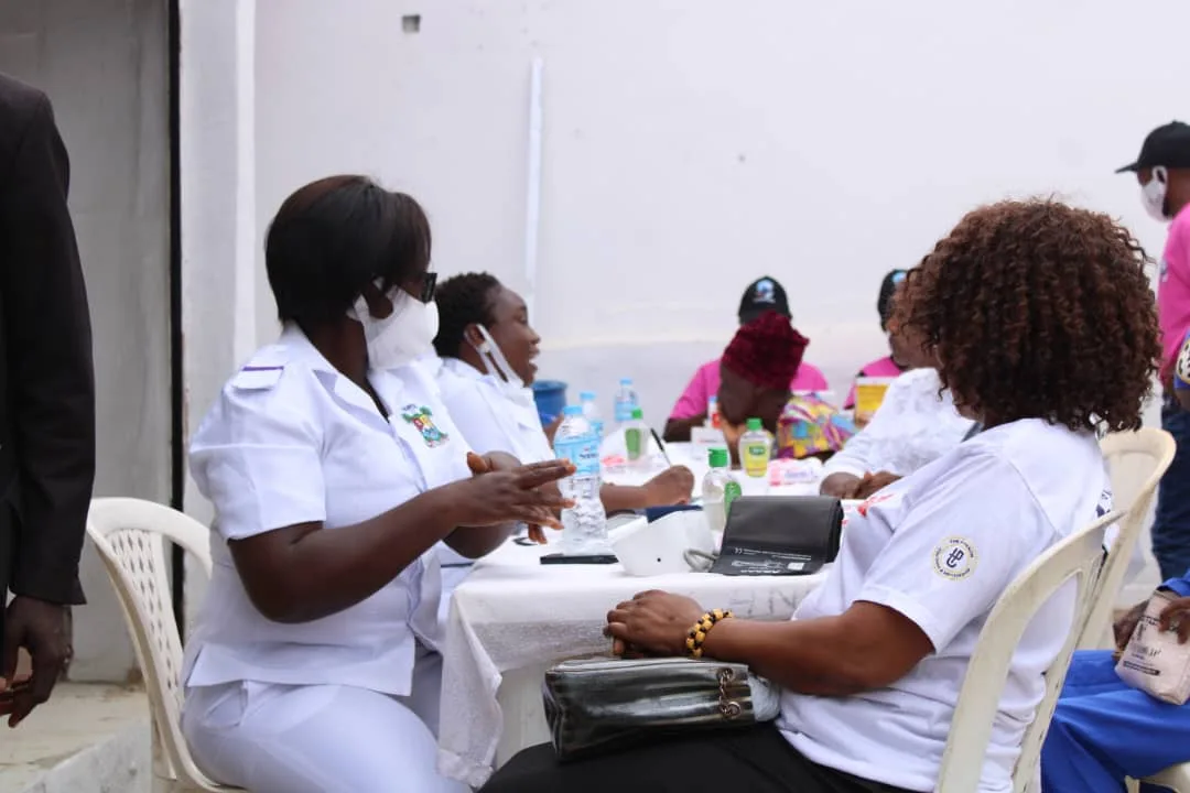 Nurses in white uniforms seated at a consultation table with patients