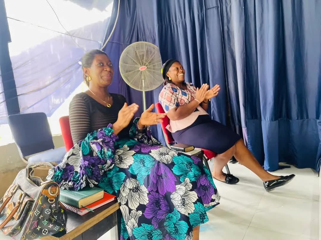 Two women worshipping from their seats, one clapping