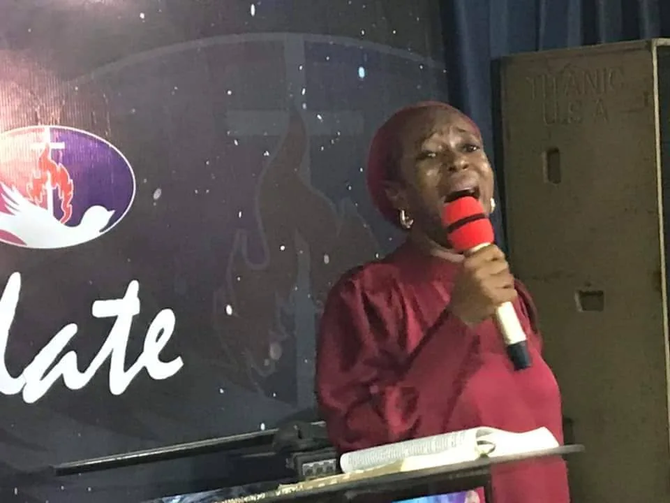 Apostle Ogochukwu Yvonne Ukwu ministering with a microphone, an open Bible on the lectern