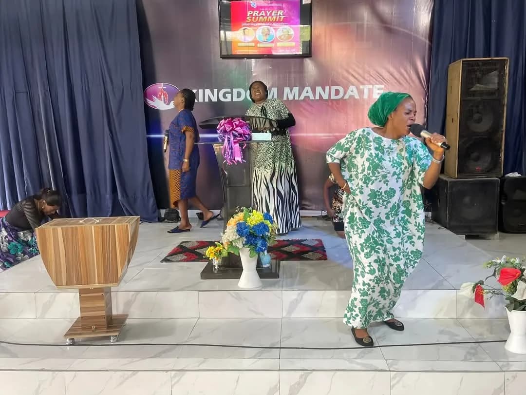 A wide view of the hall, a minister ministering beside the lectern with the summit poster on screen