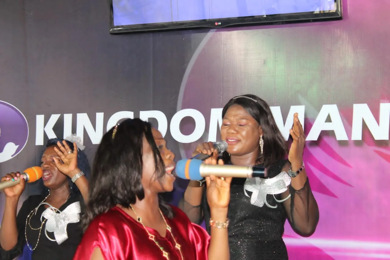 Three women singing into microphones during worship