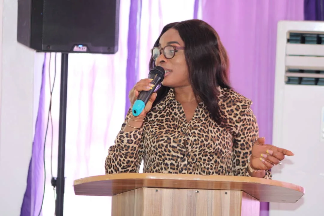 A speaker in a leopard-print blouse addressing the summit from the lectern