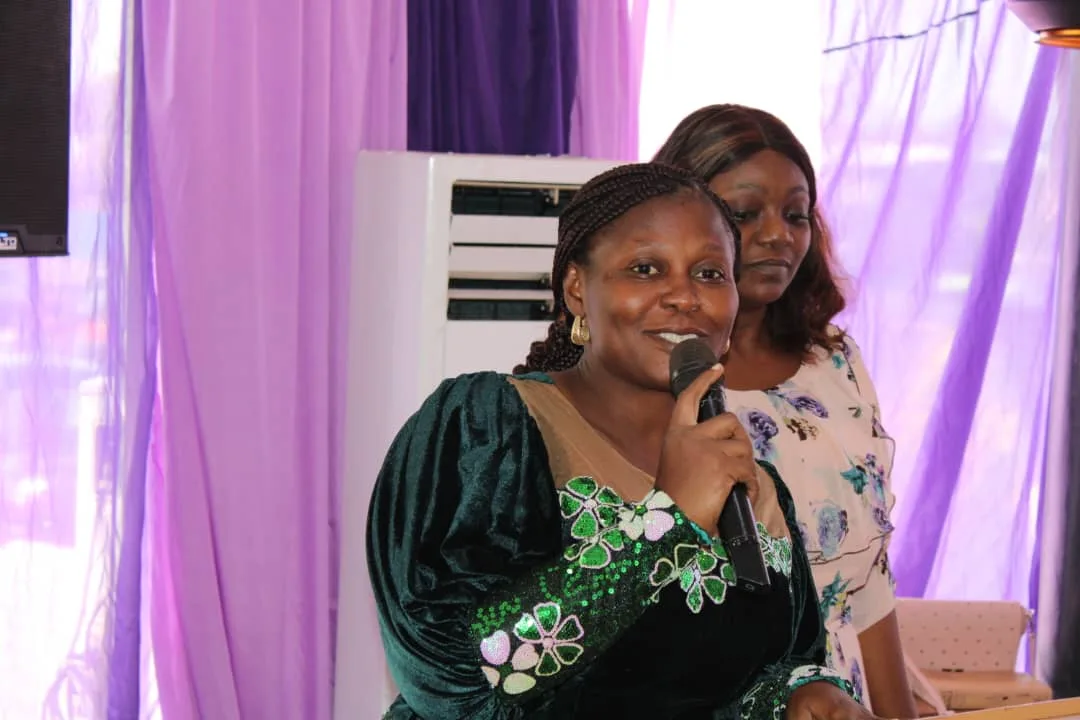 A minister in a green sequinned gown speaking into a microphone