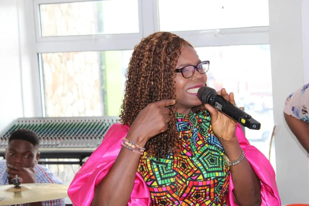A minister in a bright pink wrap singing into a handheld microphone