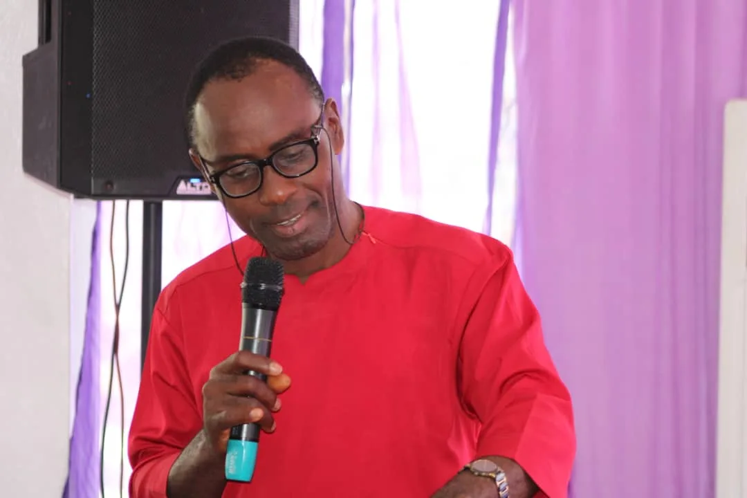A speaker in a red tunic addressing the summit with a microphone