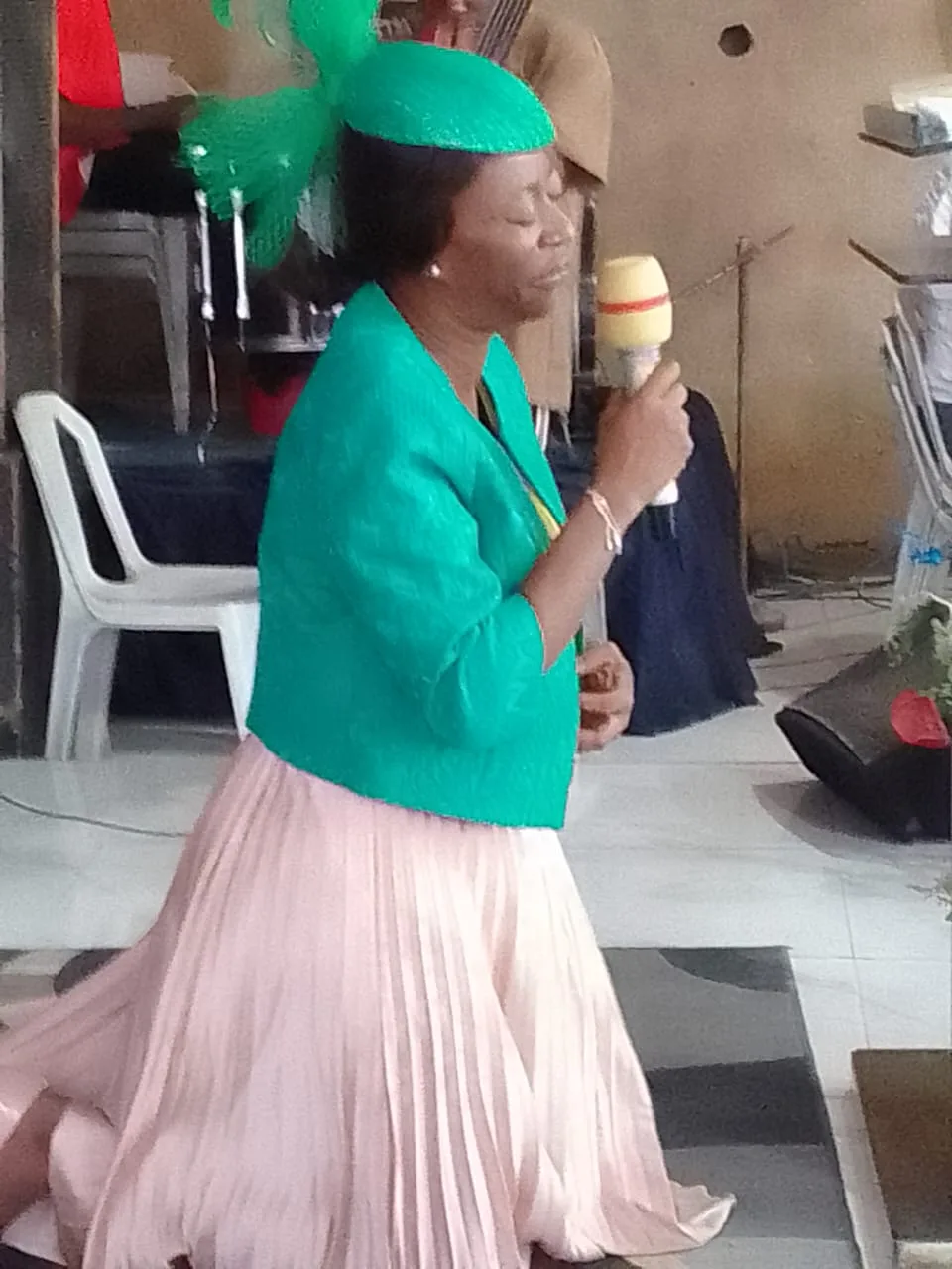 A minister praying on her knees with a microphone during a service